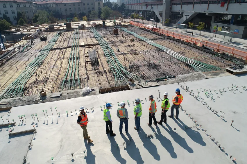 Construction professionals walking a concrete deck beside reinforcement and conduit