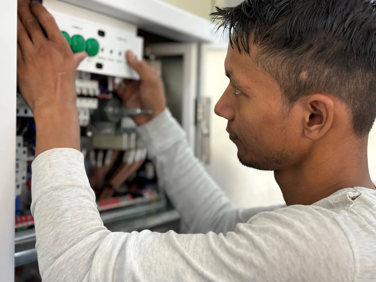An electrician fitting a control panel cover beside circuit wiring
