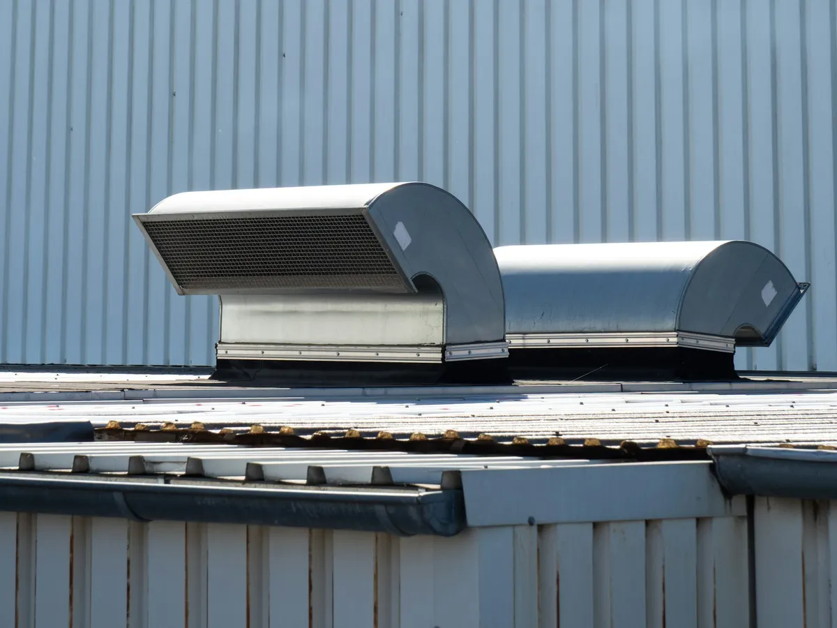 Two metal ventilation units on the roof of an industrial building